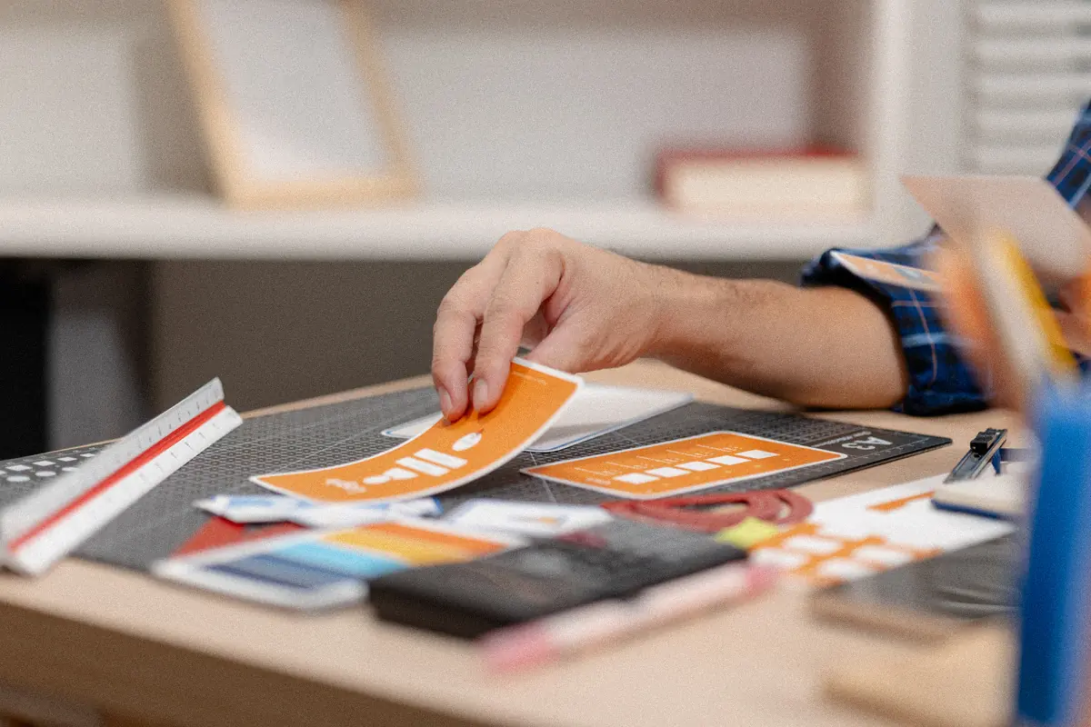 Designer comparing printed logo cards and colour options on a desk: building a startup brand identity