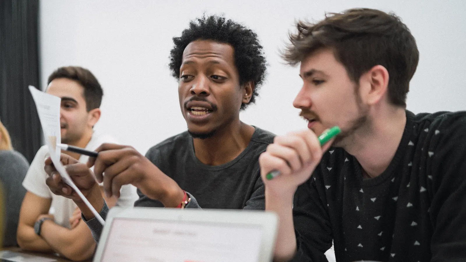 Three colleagues in discussion around a tablet in a bright office: branding for startups and small businesses