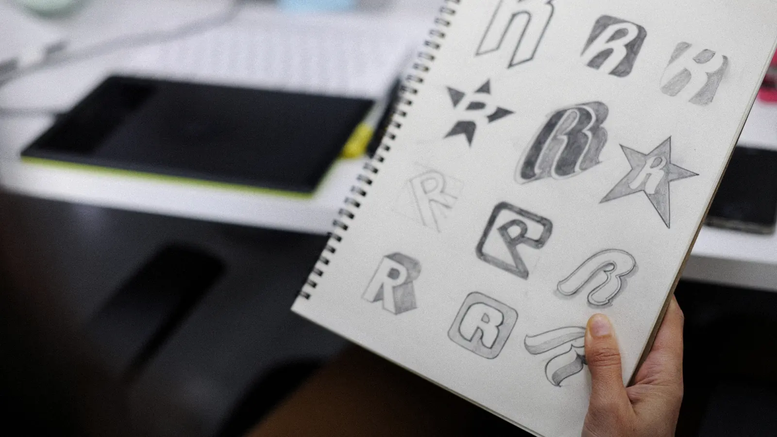 Carnet de croquis couvert d’essais de logos au crayon : créer un logo gratuitement, avec une IA ou avec un graphiste