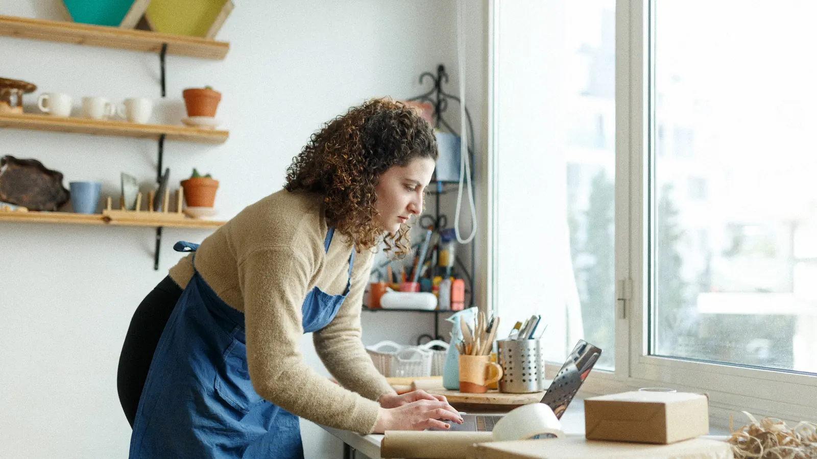 Small business owner working on her laptop in her ceramics studio: email marketing flows for an online store