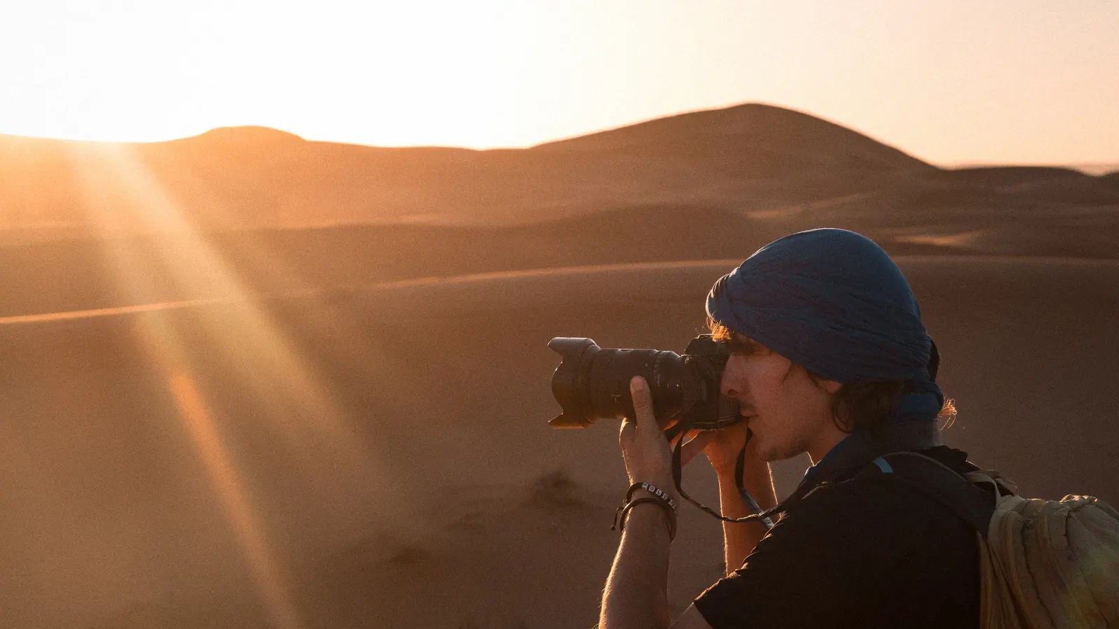 Photographer shooting at sunset in the Merzouga dunes of the Sahara: Morocco photoshoot guide to locations, permits and seasons