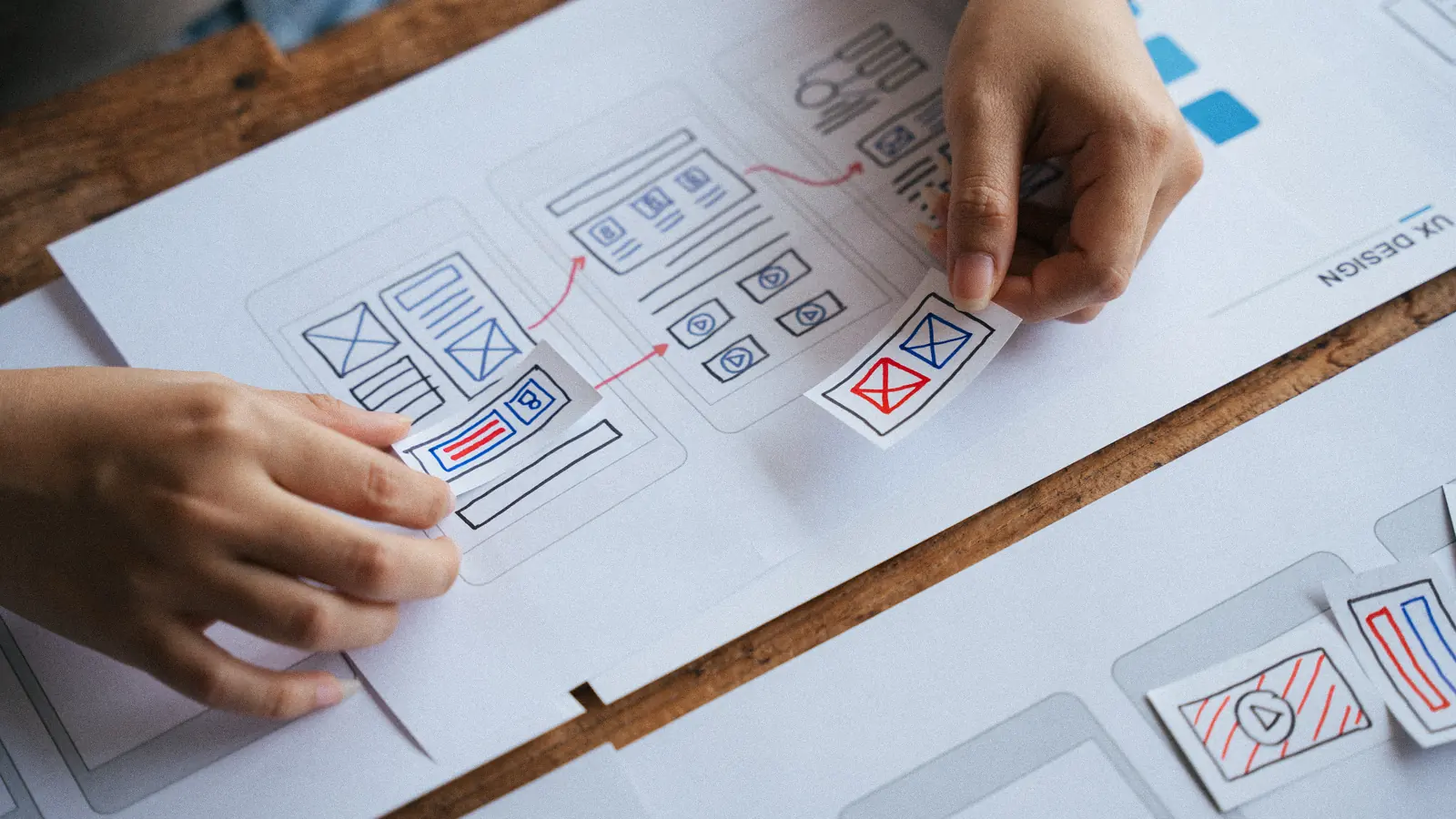 Mains organisant les maquettes filaires d’un site sur une table : refonte de site internet sans perdre son référencement