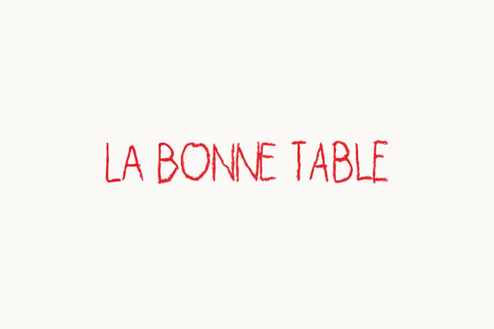 The one-line La Bonne Table logotype in red pastel on white