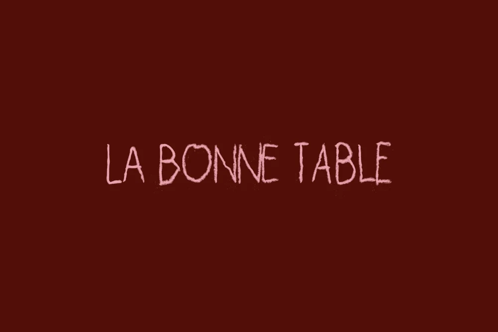 شعار La Bonne Table في سطر واحد بالباستيل الوردي على العنابي