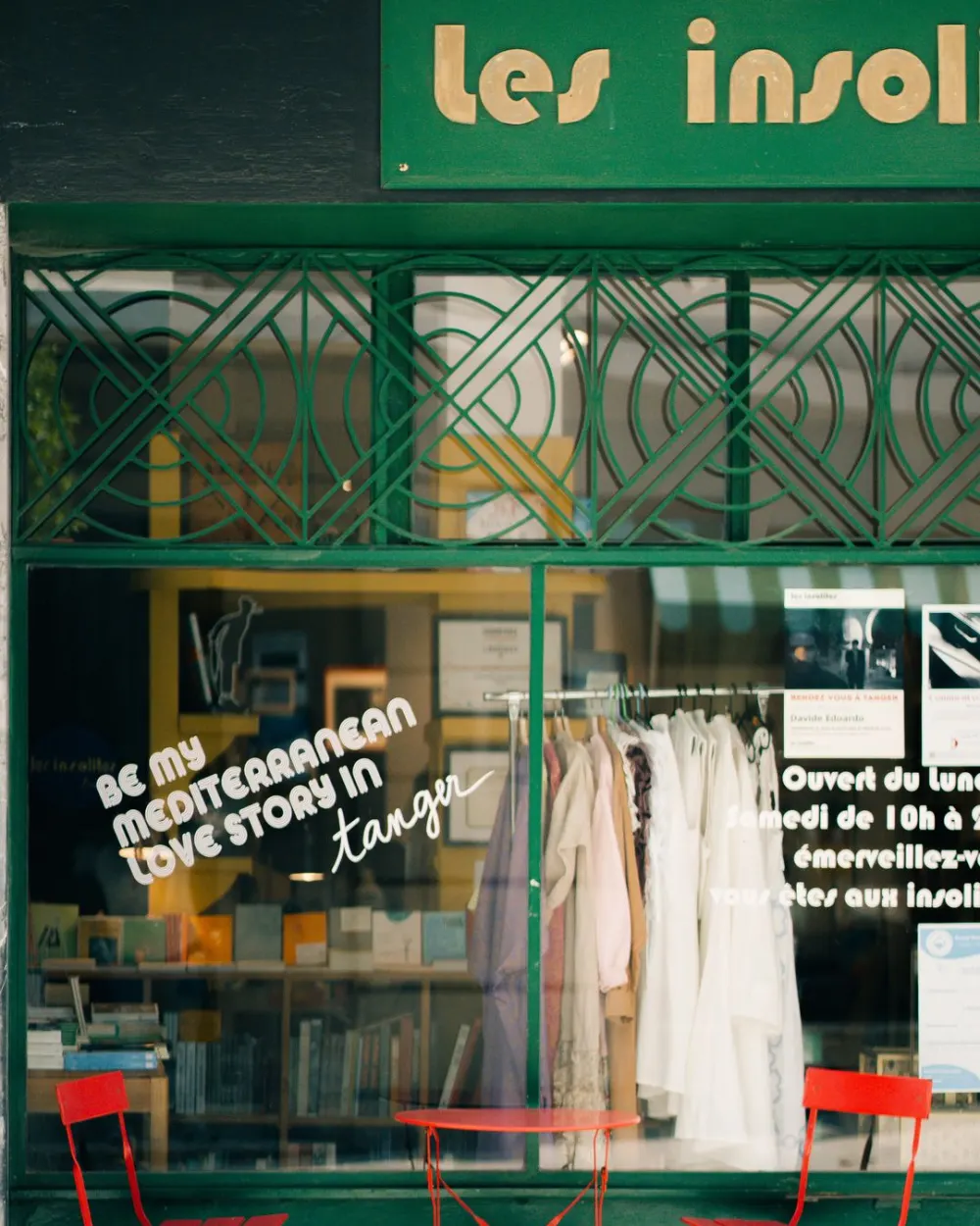 The green storefront of Les Insolites in Tangier with red chairs
