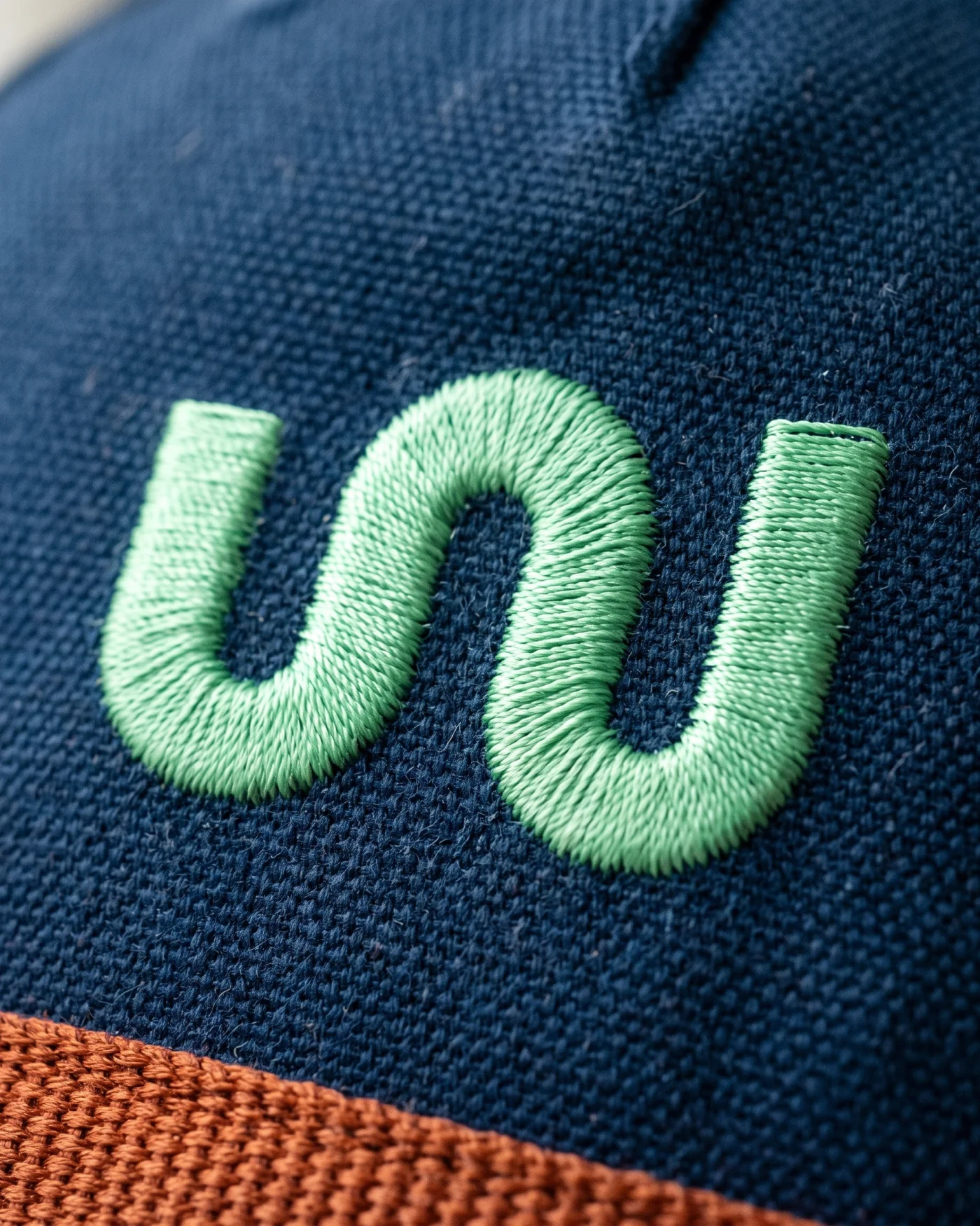 The W monogram embroidered in mint thread on navy canvas, close up